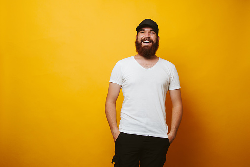 Portrait of young smiling bearded man wearing white t-shirt and black cap