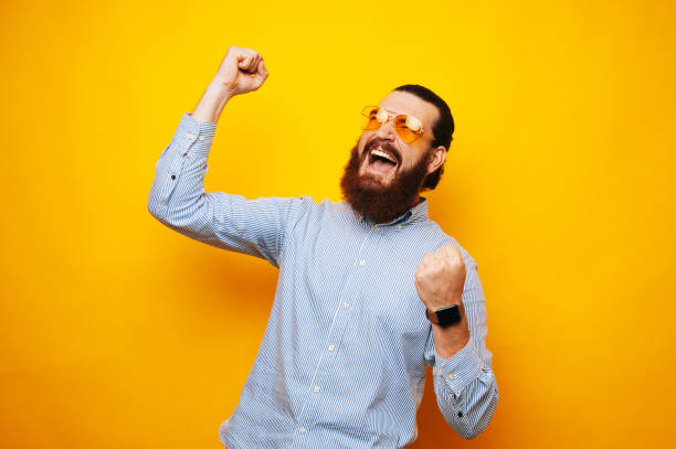 istock Joyful bearded man celebrating success over yellow background 1195124353