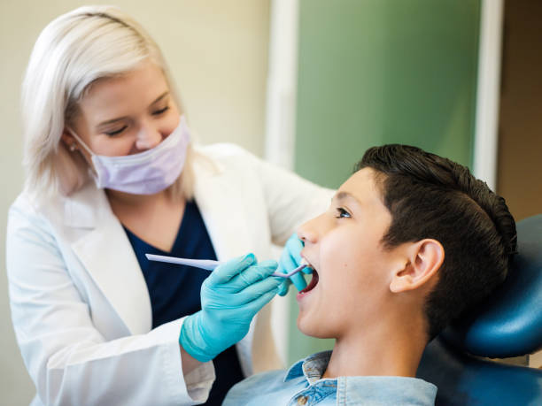 Latin boy opening mouth and dentist checking teeth