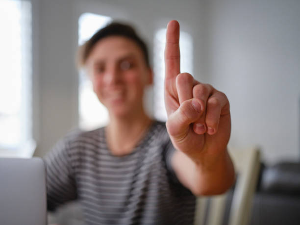 A high school student boy showing the number one gesture by pointing one finger upward.