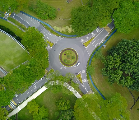 aerial view of a junction with a car and road marks in a  roundabout