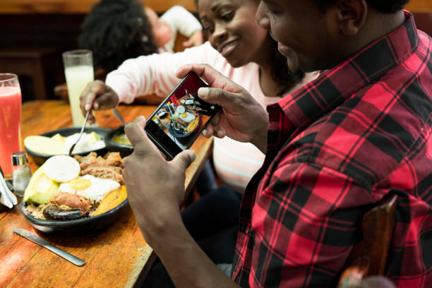 afro family che scatta una foto del piatto di bandeja paisa, un piatto tipico della pianura in colombia - bandeja paisa foto e immagini stock