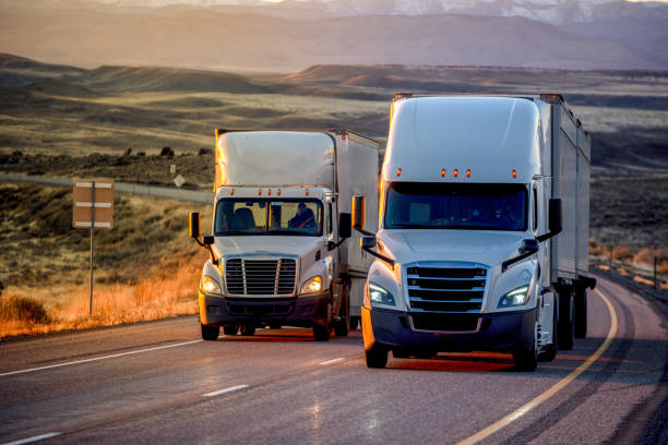 long haul semi-truck rolling down a four-lane highway at dusk - semi truck photos photos et images de collection