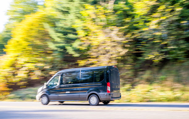 istock Black compact cargo business mini van running on the autumn road with trees on the side 1195154682