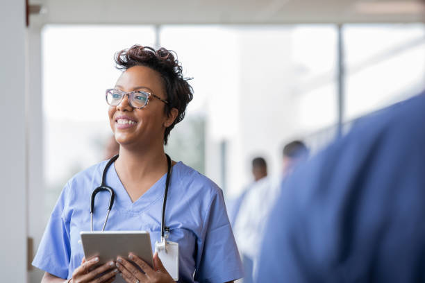 piękna pielęgniarka uśmiecha się trzymając cyfrowy tablet - female nurse nurse scrubs female doctor zdjęcia i obrazy z banku zdjęć