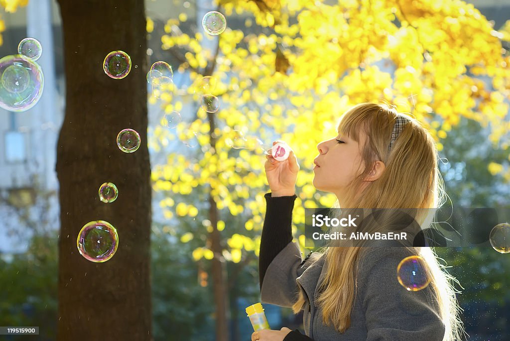 Donna soffiare le bollicine nel parco - Foto stock royalty-free di Adulto