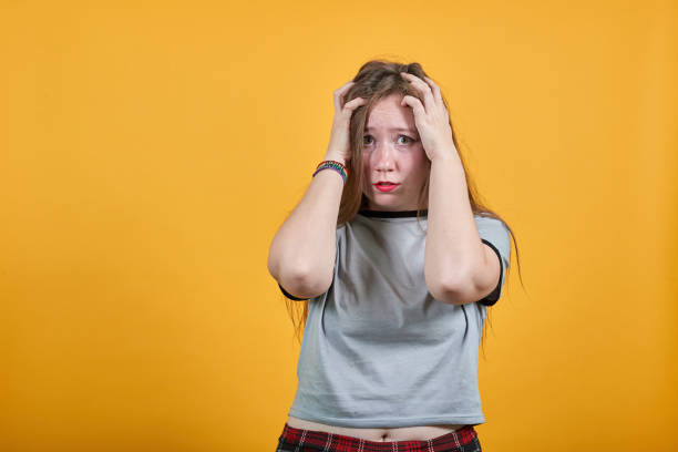 istock Scared woman in casual clothes keeping eyes opened, with hands behind head. 1195166421