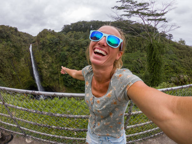 istock Woman taking selfie with waterfall in Hawaii 1195168106