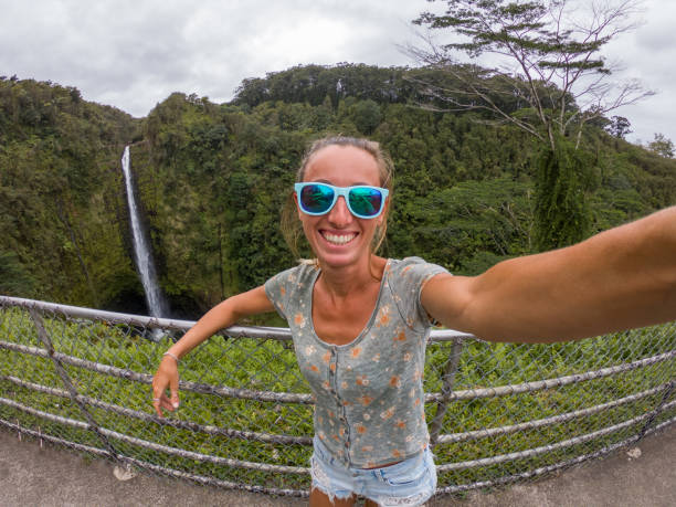 istock Woman taking selfie with waterfall in Hawaii 1195168228