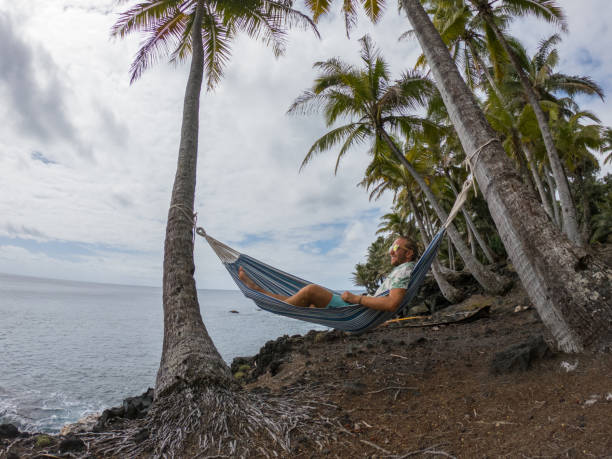 istock Man relaxing on hammock hanging on palms by the beach 1195168248