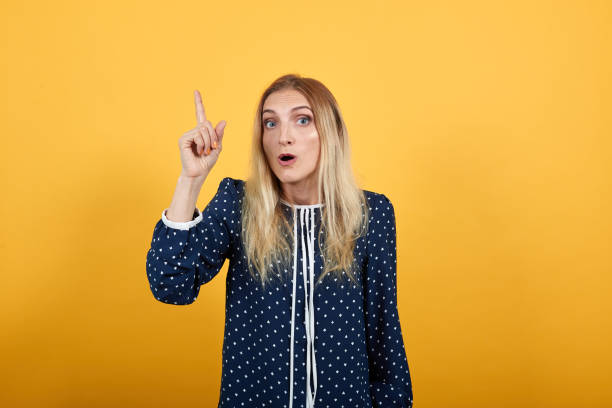 istock Shocked young woman having idea, pointing up with opened mouth 1195170826