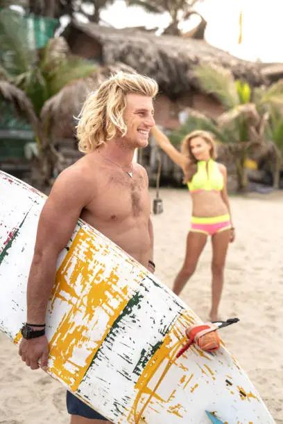 Photo of Blond surfer standing with his girlfriend on a beach in Vietnam