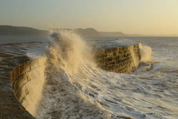 Big waves splashing on the Cobb in Lyme Regis, Dorset caused by gusty winds during high tide
