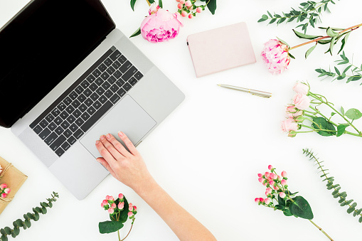 Woman work at laptop. Hand with laptop and flowers with eucalyptus branches on white background. Flat lay. Top view