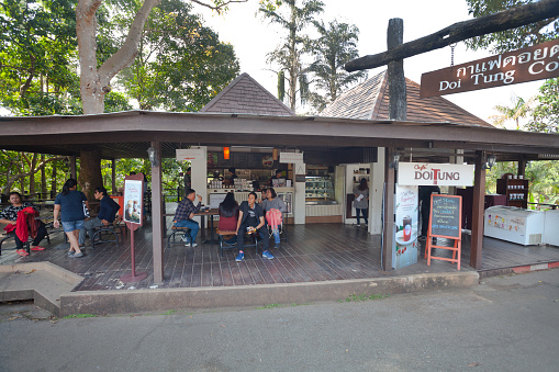 Doi Tung coffee shop and tourists on mountain in Chiang Rai - people are having a break. Doi Tung mountain in thai highlands of  Mae Fa Luang District in provinz Chiang Rai. On mountain is coffee plantation with same name brand of mountain.