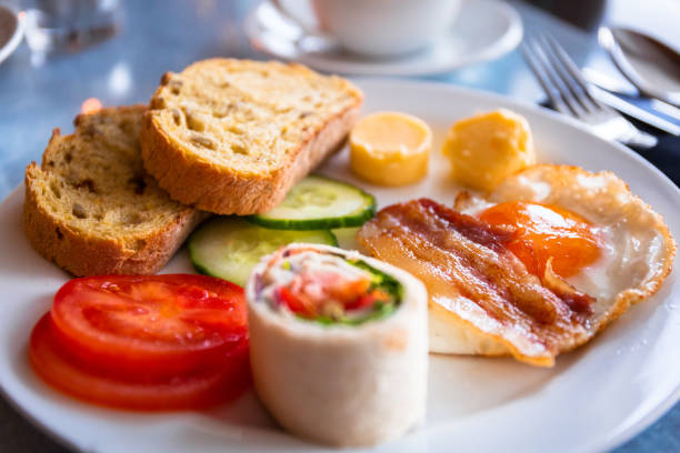 Tasty breakfast on the plate. Fried egg with bacon, bread, butter and salad.