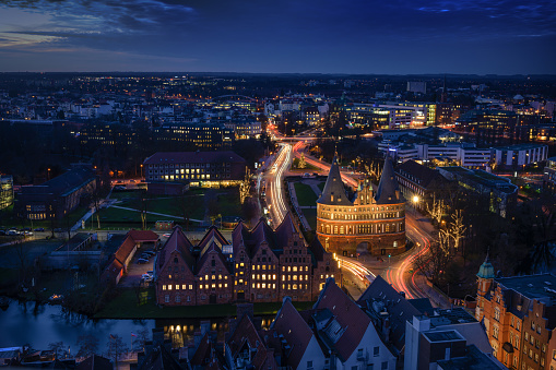 Aerial night view of the illuminated city of Luebeck, Germany in winter with Holstentor and historic Salzspeicher houses, long term exposure at blue hour, copy space
