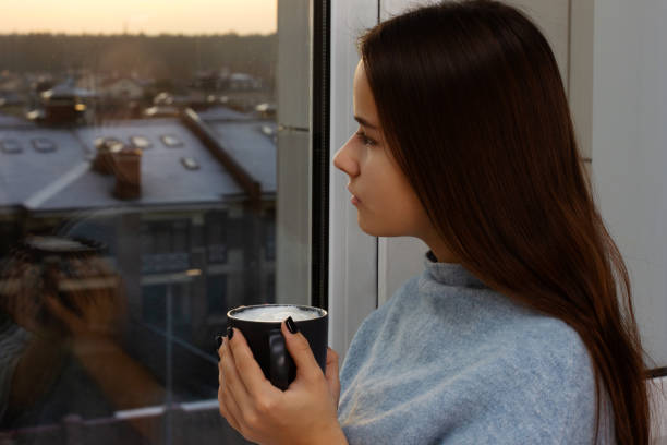 istock Nice girl drinks coffee and looks out the window at sunset 1195187762