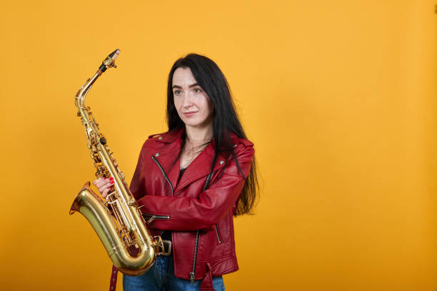istock Pretty young man in red jacket posing keeping gold saxophone with sceptic face 1195190924