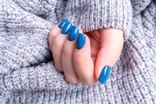 istock Delicate female hand with perfect blue manicure. Warm knitted grey background 1195190956