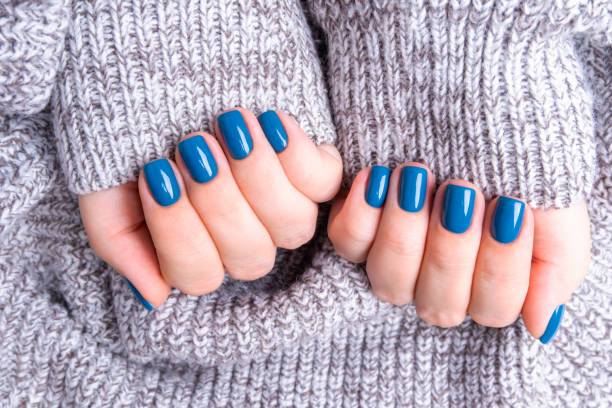 istock Delicate female hands with perfect blue manicure. Warm knitted grey background 1195190966