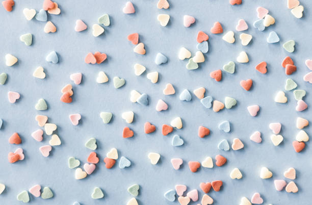colorful sugar heart shaped sprinkles on pastel blue background. valentines day concept. - heart shape confetti small red imagens e fotografias de stock