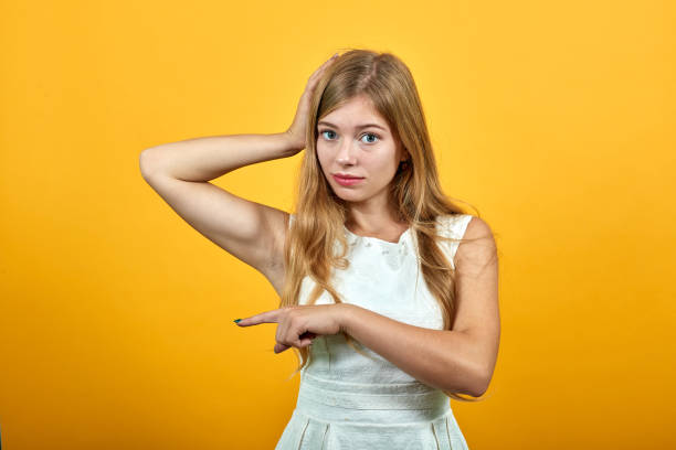 istock Serious woman keeping hand on head, holding other hand aside, looking sad 1195199584