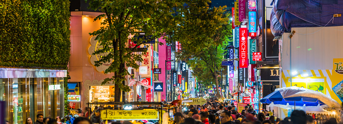 Crowds of shoppers along the pedestrianised streets of Myeong-dong overlooked by the neon lights of stores in the heart of Seoul at night, South Korea’s vibrant capital city.