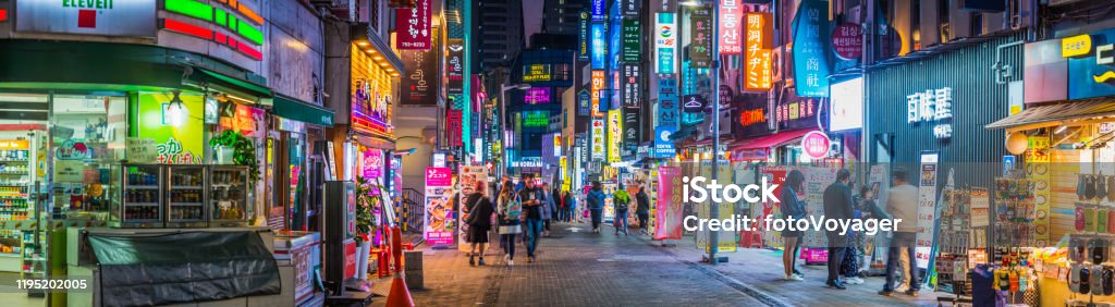 Neon night shopping street Myeong-dong shopping district panorama Seoul Korea Crowds of shoppers along the pedestrianised streets of Myeong-dong overlooked by the neon lights of stores in the heart of Seoul at night, South Korea’s vibrant capital city. Seoul Stock Photo