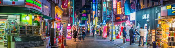 Crowds of shoppers along the pedestrianised streets of Myeong-dong overlooked by the neon lights of stores in the heart of Seoul at night, South Korea’s vibrant capital city.