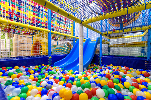 Kids playground indoor. Panoramic view inside the dry pool with colorful balls and slide. Nice plastic gym for activity in playroom. Children playground for sport and play in kindergarten.