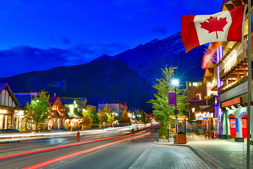 Canadian flag with Banff Avenue at twilight time, Alberta, Canada