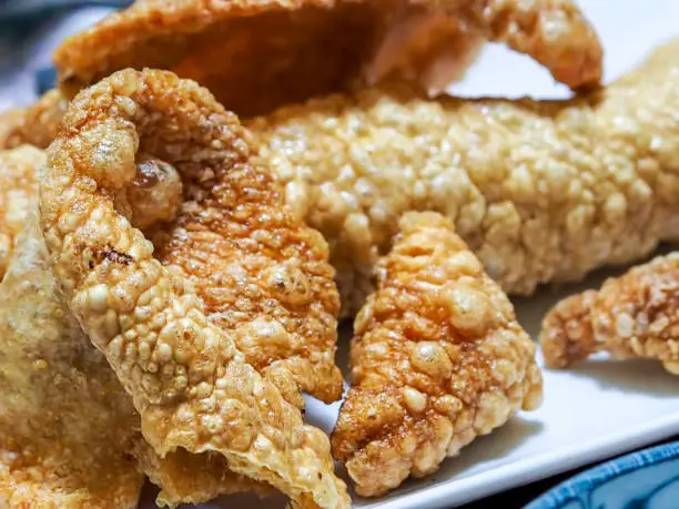 Photo of Large pieces of freshly fried and roasted crackling pork rind (skin) on a serving plate