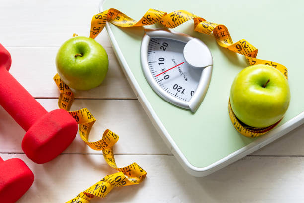 dieta e conceito saudável do peso da perda de vida. maçã verde e escala de peso medir torneira com vegetais frescos e equipamentos esportivos para as mulheres dieta emagrecimento. - peso - fotografias e filmes do acervo