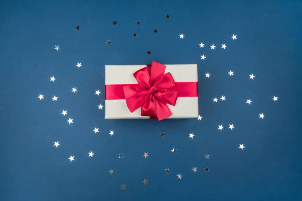 istock Gift box with big red bow on blue background with silver sequins 1195206685