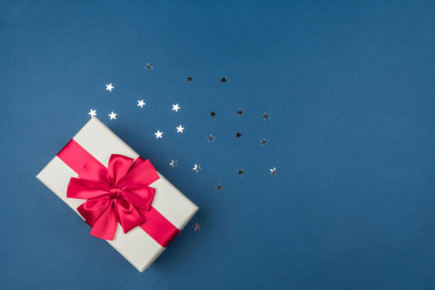 istock Gift box with big red bow on blue background with silver sequins 1195206686