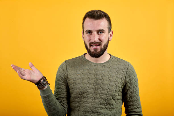 istock Young handsome caucasian man pointing with palm aside, looking calm 1195212557