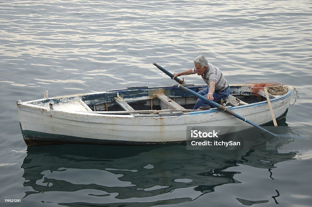 Anziano pescatore in una barca - Foto stock royalty-free di Barca a remi