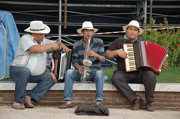 Three street musicians playing with accordions and a saxophone.