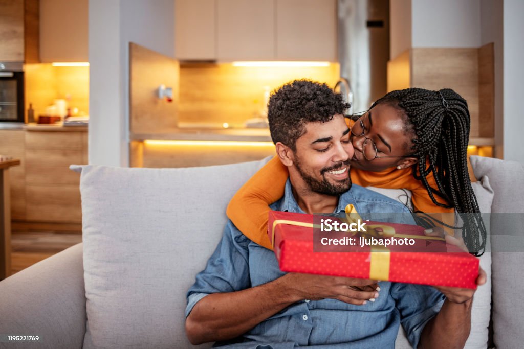 Couple in love celebrating birthday Romantic Couple Exchanging Christmas Gifts At Home. Husband And Wife Affectionately Exchanging Christmas Gifts Gift Stock Photo
