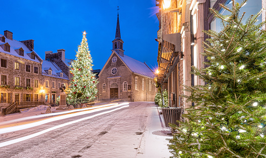 The illuminated streets of the beautiful old town of Quebec during the Christmas holidays. Petit Champlain district and Place Royale with its Notre-Dame-des-Victoires church. Night shot of Quebec streets.