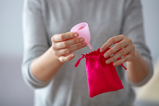 Primer plano de las manos de la joven sosteniendo la copa menstrual en el baño photo