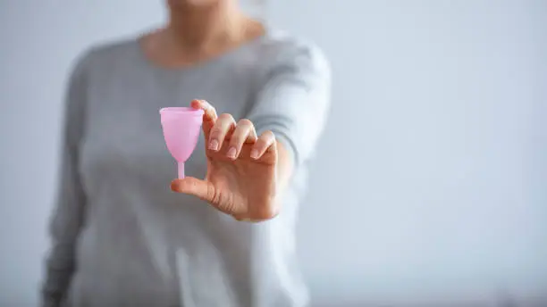 Young woman hands holding different types of feminine hygiene products - menstrual cup. Young woman hand holding menstrual cup. Selective focus.