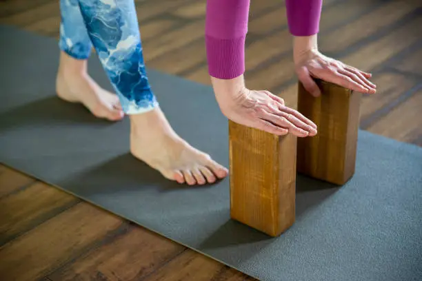 Women practicing yoga therapy, stretching in down dog using blocks and the wall, downward facing dog, exercise for spine and shoulders flexibility, working out, closeup