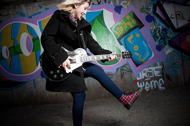 Female rock musician with electric guitar posing on white background