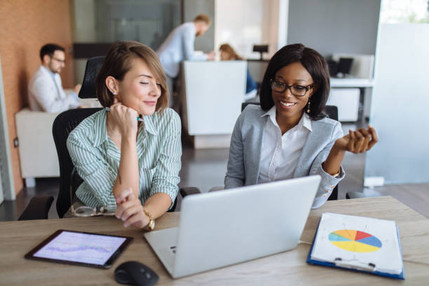 istock Businesswomen with laptop, digital tablet and chart papers cooperating 1195242783