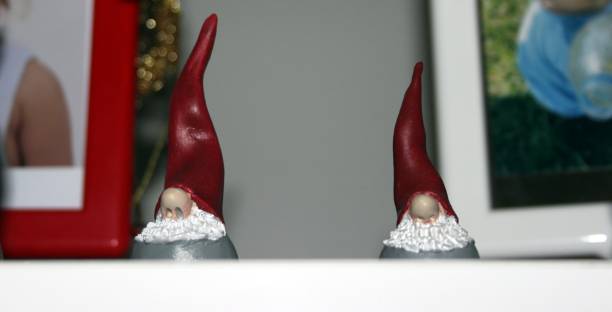 two small statues of two elves dressed in red placed on a shelf