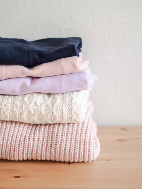 istock Stack of warm knitted woolen sweaters pastel shades and dark blue on wood table 1195246750