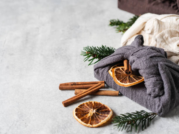 Eco-friendly fabric reusable gifts packaging with fir brunch, cinnamon stick and dry orange slice. Christmas reusable sustainable gift wrapping alternative. Zero waste concept. Copy space