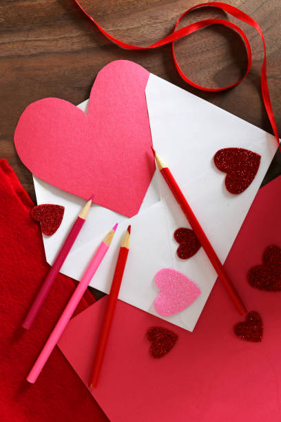 tarjeta de san valentín en forma de corazón en sobre en la mesa con suministros de arte - pencil colors heart shape paper fotografías e imágenes de stock